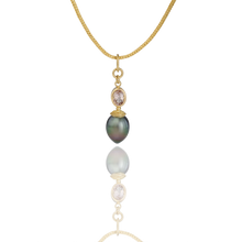 Load image into Gallery viewer, A collectors charm! An iridescent pearl whose color moves from deep green through bronze, is paired with tanzanite - a stone normally associated with blues and violet blues. The buttery tones of high karat gold in the granulated cap give texture and warmth to the gem and pearl, making this a collector's piece indeed. Length approx. 39mm, width 10.3mm (L 1.5in W .4in). Made from recycled 22k gold, a 13.7x10.3mm cultured Tahitian pearl and D Block natural tanzanite (.88ct). Chain is available separately.