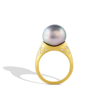 Load image into Gallery viewer, A luminous soft silver blue toned perfectly round pearl is surrounded by sparkling graduated diamonds scattered along the curves surrounding the pearl. A parchment like texture gives a soft papery feel to the fingertips and a satiny look to the gold.

Made in recycled 22k yellow gold, Canadian diamonds (.30ct) and a cultured Tahitian pearl. Size 7. Can be resized. One of a kind. This ring can be made with other pearl options, please contact concierge@atelierwolff.com to discuss.